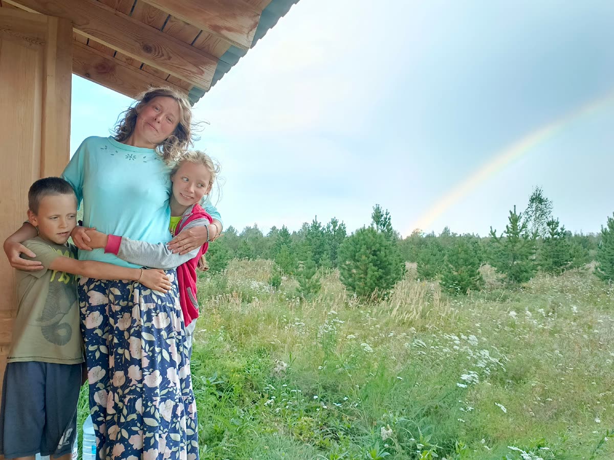 A mother and her children on their domain, a rainbow over the field behind them
